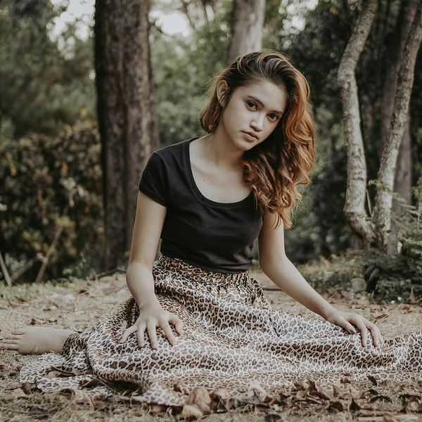 A person looking peaceful with eyes closed in a natural setting.